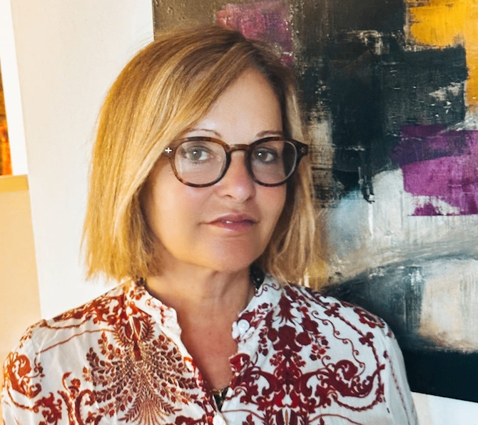 Ritratto di una donna con occhiali e camicetta fantasia davanti a un dipinto astratto, esperta di separazione e divorzio a Firenze