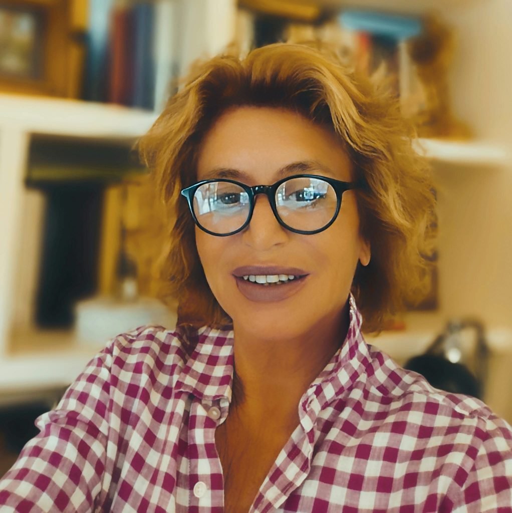 Ritratto di donna sorridente con occhiali e camicia a quadri davanti a scaffali di libri, esperta di separazione e divorzio a Firenze